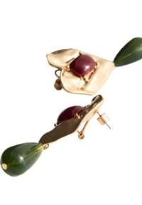 Des boucles d'oreilles dorées présentent un design de feuille, avec une pierre rouge profond au centre et un accent de goutte verte, mettant en valeur une finition texturée.