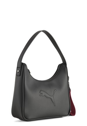 Sac à bandoulière en cuir noir avec une fermeture éclair courbée sur le dessus, logo Puma embossé à l'avant, et une sangle en tissu rouge attachée sur le côté.