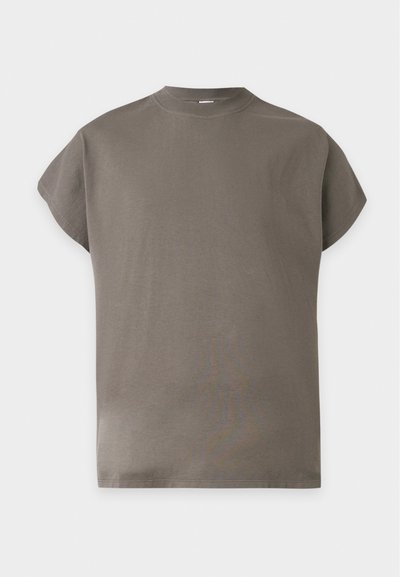 Κοντομάνικο, σκούρο μπεζ T-shirt με στρογγυλή λαιμόκοψη και άνετη εφαρμογή σε απλό ανοιχτό γκρι φόντο.