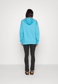 Ljusblå hoodie med huva, oversized passform och ribbade ärmslut, som matchas med svarta leggings och svarta plattformsskor. Enkel och avslappnad design.