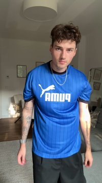 Jersey atlético azul con rayas verticales, que presenta un logo y letras en blanco. Mangas cortas, tejido cómodo, ajuste casual.