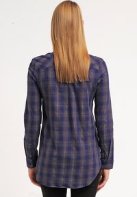 Camicia a maniche lunghe a scacchi in blu scuro, con accenti grigio chiaro, colletto button-down e orlo curvo. Materiale in cotone morbido.