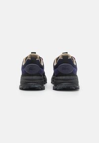 Zapatillas deportivas negras y azul marino con un upper texturizado, acentos en beige contrastantes y un collar acolchado. Presenta una suela de goma duradera.
