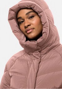 Lavendel Puffermantel mit einer hohen, gerafften Kapuze. Verfügt über eine Knopfleiste vorne und eine gesteppte Textur. Weiches, leichtes Material.