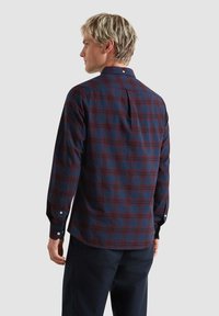 Camicia a maniche lunghe a quadri in blu scuro e bordeaux, con colletto a bottoni e una singola piega sul retro, realizzata in tessuto morbido.