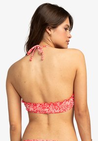Červený kvetinový bikiny top s volánikmi, nastaviteľnými šnúrkami vzadu a hladkým, elastickým materiálom.