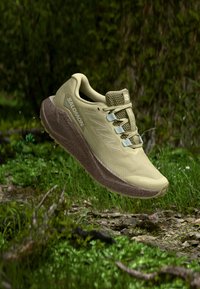 Light khaki trail running shoe with a textured mesh upper, padded collar, and beige rubber sole featuring a distinct tread pattern.