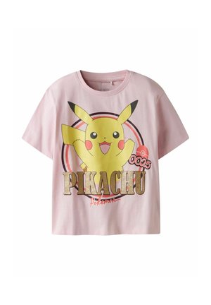 Chemise rose à manches courtes présentant un grand Pikachu souriant avec les bras levés, entouré de cercles et du texte "PIKACHU" et "Pokémon."