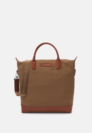 Canvas tote bag in brown with leather accents. Features dual handles and a detachable strap, with a logo on the front pocket.