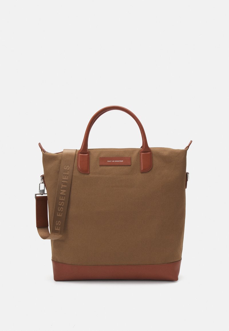 Saco tote em canvas castanho com acabamentos em pele. Apresenta alças duplas e uma alça destacável, com um logótipo no bolso frontal.