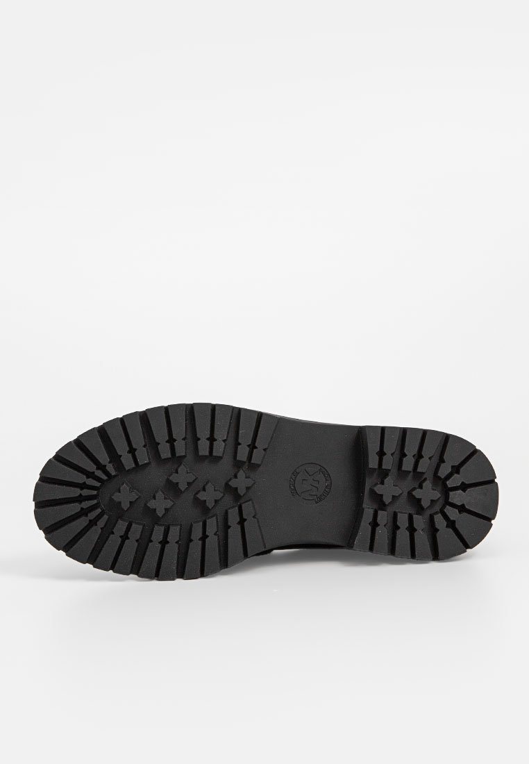 Suola di stivaletto in gomma nera con un motivo a battistrada robusto, caratterizzato da profonde scanalature e un logo centrale, progettata per offrire trazione e durata.