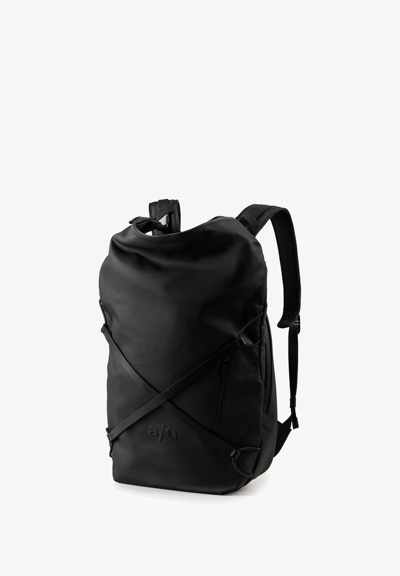Zwarte rugzak van waterdicht materiaal, met verstelbare banden, een handvat aan de bovenkant en een voorzak met rits. Heeft een minimalistisch ontwerp.
