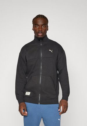 Sort zip-up sweatshirt med høj krave, strikket stof og dobbelte forlommer. Har et guld Puma-logo på brystet og et mærke på kanten.