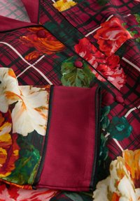 Floral-patterned fabric in vibrant colors features a burgundy plaid with large flowers. Includes a breast pocket and contrasting trim.