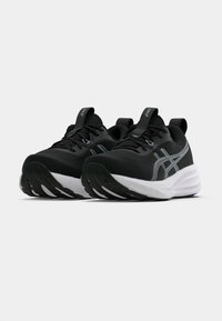 Čierne športové topánky s textúrovaným zvrškom, bielou medzipodrážkou a čiernou podrážkou. Majú reflexné strieborné prvky a dekoratívne prešívanie.