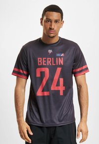 Pánsky čierny športový dres s červenými akcentami, s výrazne potlačenými nápismi "BERLÍN" a "24". Ľahký sieťovaný materiál, krátke rukávy, okrúhly výstrih.