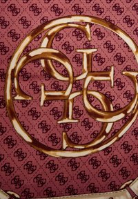 Gemusteter Stoff mit goldfarbenem, ineinandergreifendem Logo-Design auf einem mauvefarbenen Hintergrund mit wiederholten kleinen Logodetails. Strukturierte Optik.