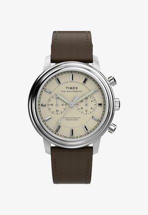 Montre chronographe Timex Waterbury avec un boîtier en acier inoxydable, un cadran beige, un bracelet en cuir marron et des index horaires bien visibles. Résistante à l'eau jusqu'à 50 m.