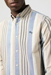 Camisa de botones con rayas verticales en beige, azul y gris. Tejido de algodón suave con un logotipo bordado cerca del pecho.