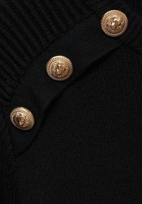 Tissu noir tricoté avec une texture côtelée et quatre boutons dorés imposants, chacun embossé d'un motif de lion.