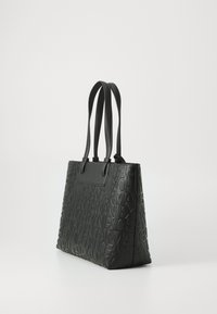 Black leather tote bag with embossed logo design, featuring two long handles and a structured shape. Smooth texture with flat base.