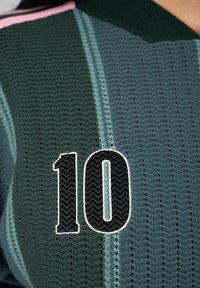 Maillot de sport tricoté avec le numéro 10 en noir et blanc sur un tissu vert foncé et bleu à rayures verticales.