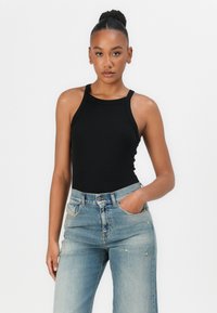 Black ribbed tank top with thin straps, paired with light blue high-waisted denim jeans featuring a slight distressed detail.