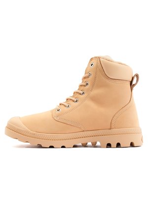 Botte de randonnée en cuir tan avec un design montante, bout rond, œillets en métal et une semelle en caoutchouc texturé avec des crampons profonds pour une meilleure adhérence.