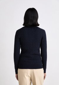 Navy knitted sweater with cables, fitted design, ribbed hem and cuffs, long sleeves. Wool or similar fabric, displayed from the back.