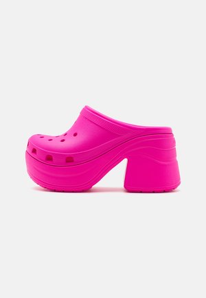 Pink foam clogs with a chunky heel, featuring ventilation holes on the upper and a smooth, rounded design with textured accents.