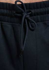 Pantaloni jogger blu navy realizzati in tessuto morbido, con vita elastica e chiusura con coulisse. Presentano dettagli cuciti e una superficie liscia.