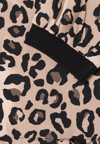 Tkanina w panterkę w odcieniach beżu i czerni, z fakturowaną powierzchnią oraz czarną elastyczną opaską przy mankiecie zapewniającą regulowane dopasowanie.