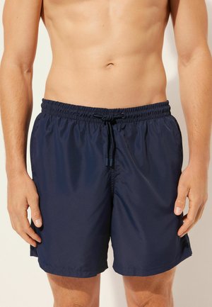 Marineblaue Badehosen aus leichtem Material, mit einem elastischen Bund und Kordelzug. Schlichtes Design, ohne Muster oder Akzente.