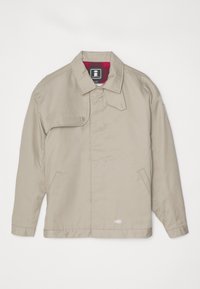 Veste beige à coupe droite, col replié, deux poches latérales et doublure à carreaux rouges. Dotée d'une fermeture par bouton et d'un patch logo au bas.