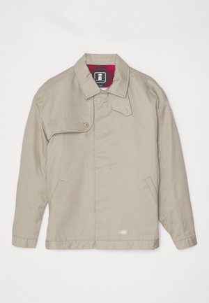 Beidzas jaka ar taisnu griezumu, salocītu apkakli, divām sānu kabatām un sarkanu paklāja oderi. Iekļauj poga aizdari un logotipa uzšuvumu apakšmalā.