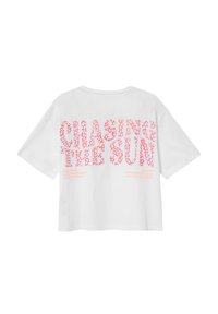 Witte katoenen t-shirt met oversized korte mouwen. Met op de achterkant roze grafische tekst "CHASING THE SUN" en aanvullende zinnen in een speelse lettertype.