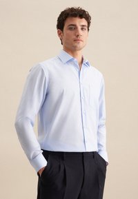 Lichtblauwe lange mouwen shirt met knoopsluiting, een borstzak en een klassieke kraag. Glad materiaal en een getailleerde pasvorm, gecombineerd met donkere broeken.