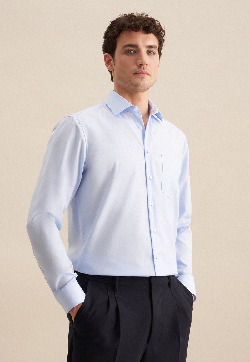 Lichtblauwe lange mouwen shirt met knoopsluiting, een borstzak en een klassieke kraag. Glad materiaal en een getailleerde pasvorm, gecombineerd met donkere broeken.