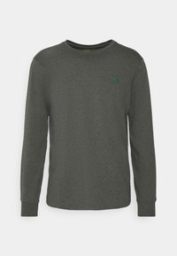 Långärmad skjorta i mörkgrå bomull med rund halsringning och grön logotypaccent på vänster bröst. Slät struktur, figurnära design.