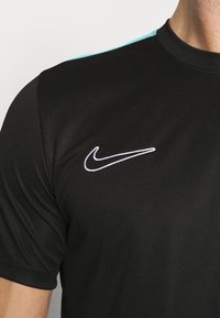 Schwarzes Sport-T-Shirt mit Rundhalsausschnitt, kurzen Ärmeln und türkisfarbenen Akzenten an den Schultern, mit einem weißen Nike-Logo auf der Brust.