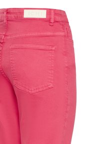 Blugi roz din denim cu buzunar posterior vizibil și etichetă de marcă pe talie, pe fundal alb.