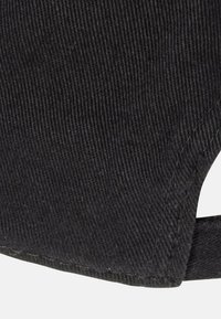 Black corduroy fabric with a ribbed texture, featuring a curved edge and visible stitching. Minimal design with no notable accents.