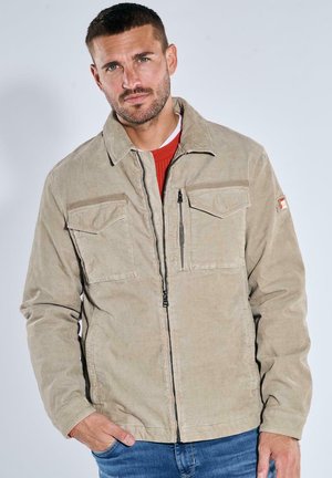 Beige corduroy jacket with a front zipper, two chest pockets and a side pocket. Features a collared neckline and cuffed sleeves.