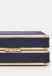 Navy blue clutch made from textured fabric with gold metal accents, featuring a rectangular shape and a secured closure.