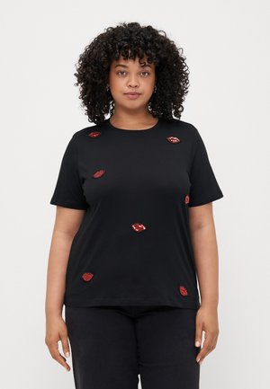 Sort T-shirt lavet af bomuld, med røde pailletlæber i forskellige positioner, korte ærmer og rund halsudskæring. Enkel og afslappet design.