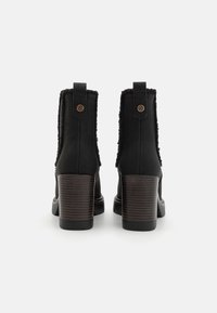 Czarne skórzane botki za kostkę z teksturowanym, futrzanym kołnierzem, słupkowym obcasem o drewnianym wykończeniu oraz dekoracyjnym guzikiem z tyłu.