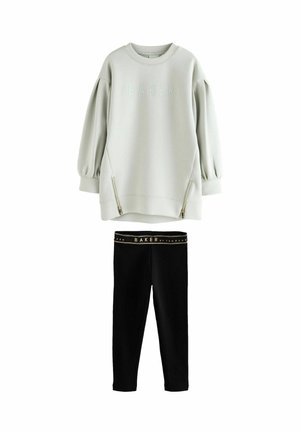 Světle šedá oversized mikina se textem "BAKER" a předními zipy, v kombinaci s černými legínami s elastickým pasem s logem značky.