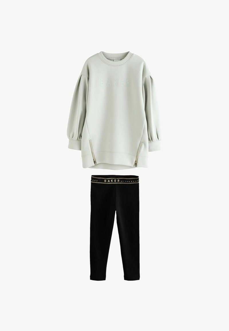 Lichtgrijze oversized sweatshirt met de tekst "BAKER" en ritssluitingen aan de voorkant, gecombineerd met zwarte leggings met een elastische tailleband met merklogo.