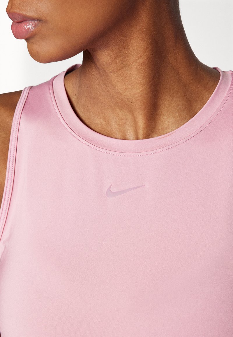 Camiseta deportiva rosa hecha de tejido suave, con un escote redondo y un sutil logotipo de Nike en el centro.