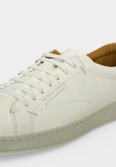 Λευκό δερμάτινο sneaker χαμηλού προφίλ με λευκά κορδόνια, λεπτομερείς ραφές και μπεζ επένδυση με επένδυση.